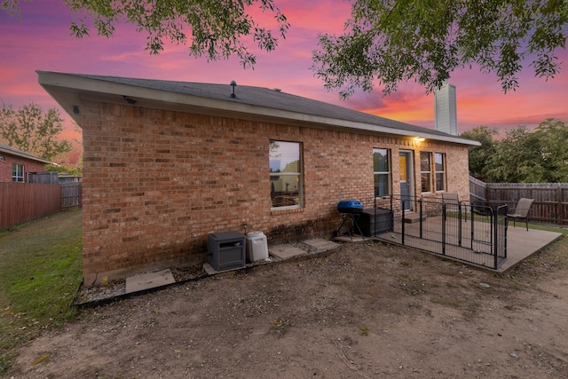 back house at dusk with ac unit and a patio area