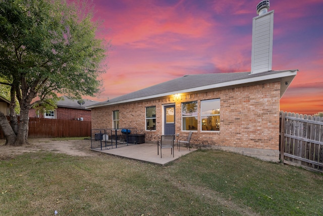 back house at dusk with a yard and a patio area