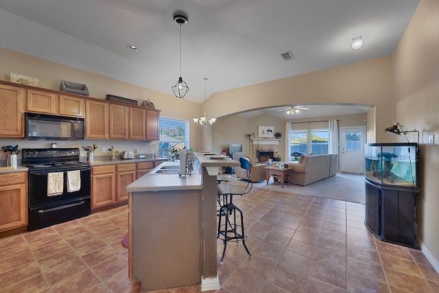 kitchen with vaulted ceiling, sink, a breakfast bar area, hanging light fixtures, and black appliances