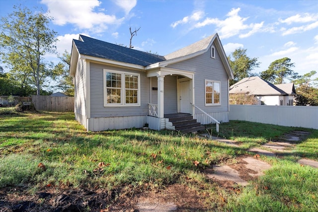 bungalow-style house featuring a front yard, roof with shingles, and fence