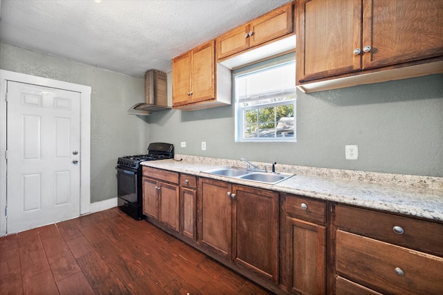 kitchen with sink, wall chimney exhaust hood, black range with gas stovetop, dark hardwood / wood-style flooring, and a textured ceiling