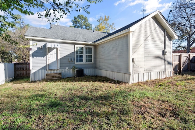 rear view of property featuring central AC unit and a lawn