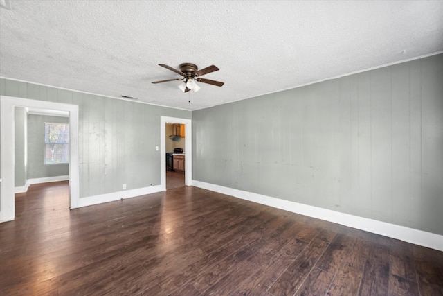 unfurnished room featuring a textured ceiling, ceiling fan, dark wood-type flooring, and wood walls