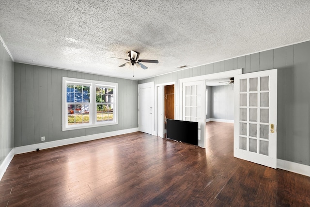 unfurnished room featuring french doors, a textured ceiling, dark hardwood / wood-style floors, and wood walls