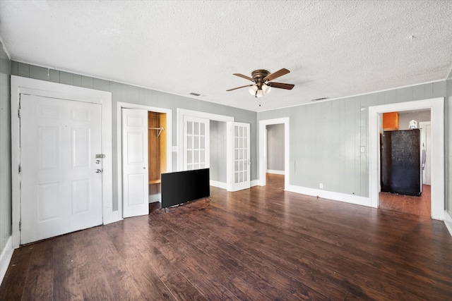 unfurnished living room featuring ceiling fan, dark hardwood / wood-style flooring, a textured ceiling, and french doors