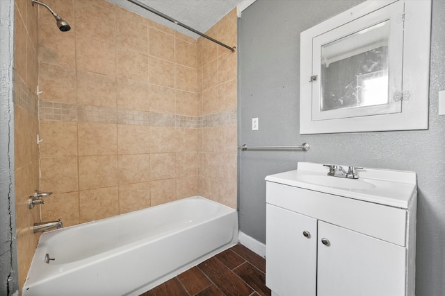 bathroom with vanity, a textured ceiling, and tiled shower / bath