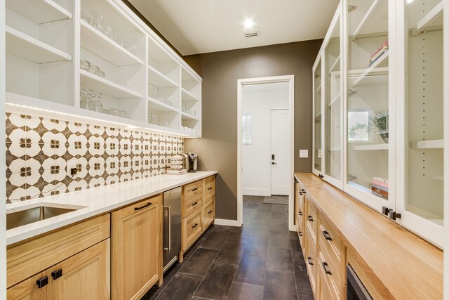 kitchen with light brown cabinets, sink, beverage cooler, dark tile patterned floors, and backsplash