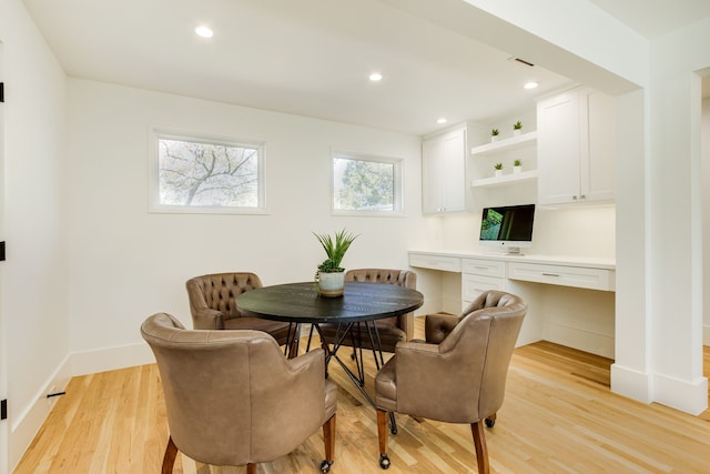 dining area with light wood-type flooring and built in desk