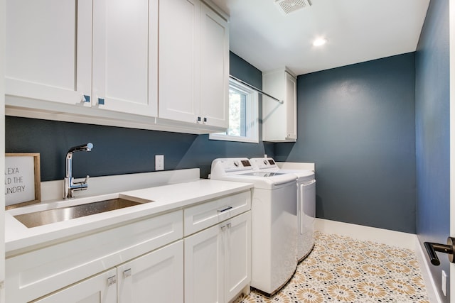 clothes washing area with separate washer and dryer, sink, and cabinets