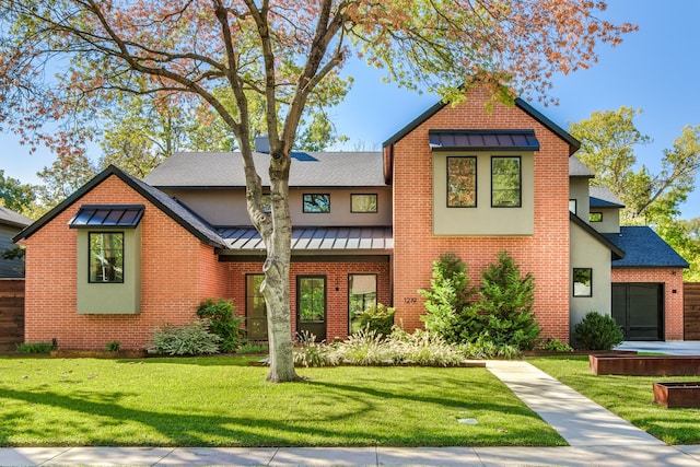 view of front of house with brick siding, a shingled roof, a front lawn, metal roof, and a standing seam roof