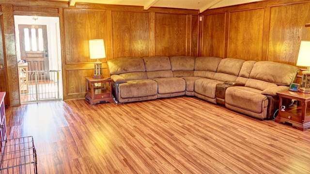 living room featuring wood walls, beamed ceiling, and light wood-type flooring