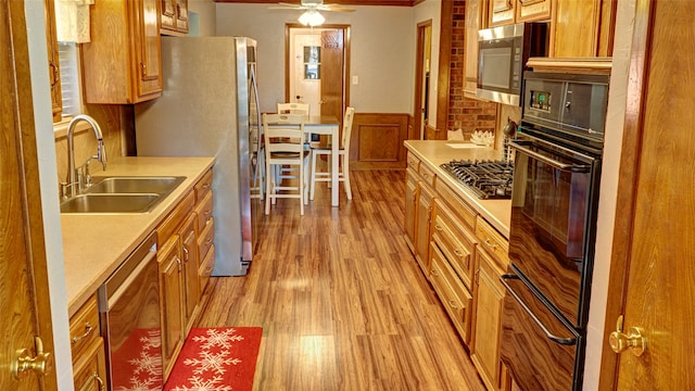 kitchen featuring stainless steel appliances, ceiling fan, light hardwood / wood-style floors, and sink