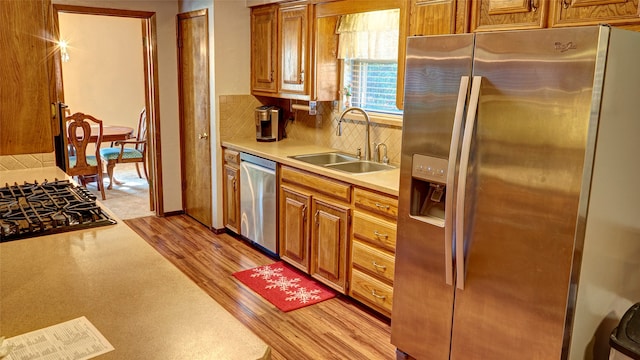 kitchen featuring backsplash, sink, light wood-type flooring, and stainless steel appliances