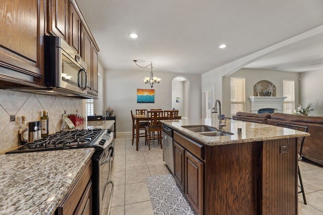 kitchen featuring sink, a kitchen island with sink, an inviting chandelier, decorative backsplash, and appliances with stainless steel finishes