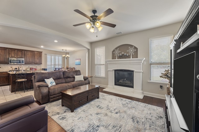 living room with plenty of natural light, light wood-type flooring, and ceiling fan with notable chandelier