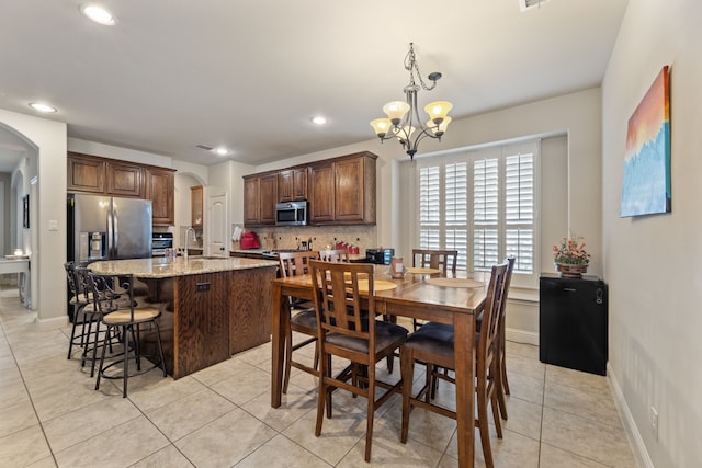 tiled dining space featuring an inviting chandelier and sink