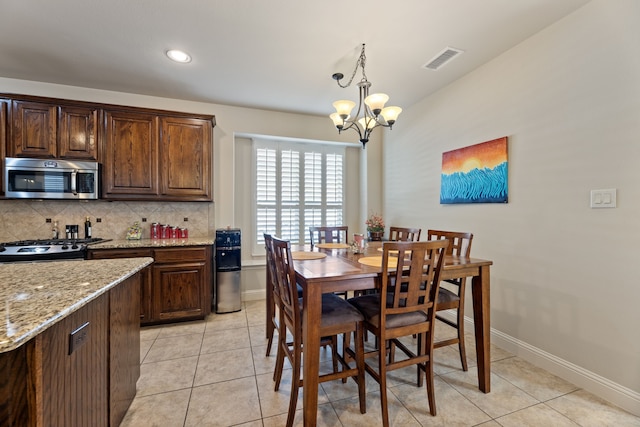 kitchen with light stone countertops, hanging light fixtures, a notable chandelier, backsplash, and appliances with stainless steel finishes