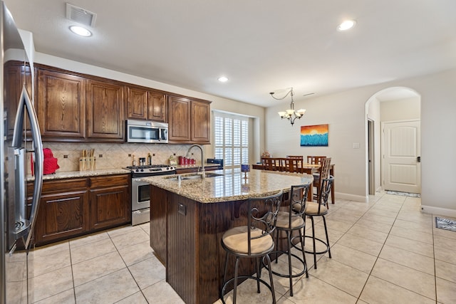 kitchen featuring sink, an inviting chandelier, an island with sink, pendant lighting, and appliances with stainless steel finishes