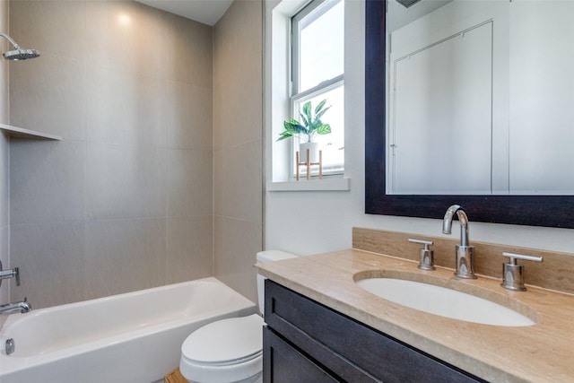 full bathroom featuring vanity, tiled shower / bath, and toilet