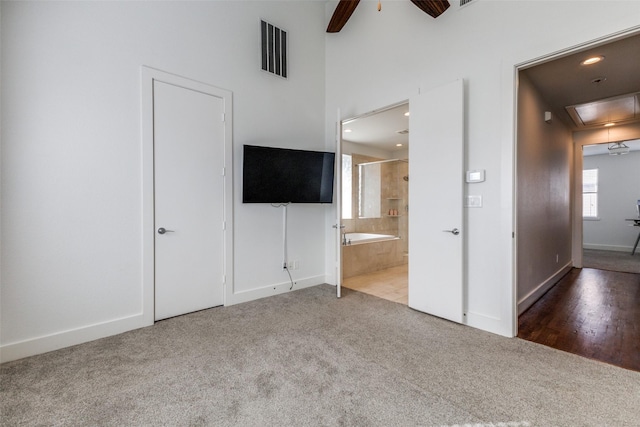 unfurnished bedroom with ensuite bath, carpet floors, and ceiling fan