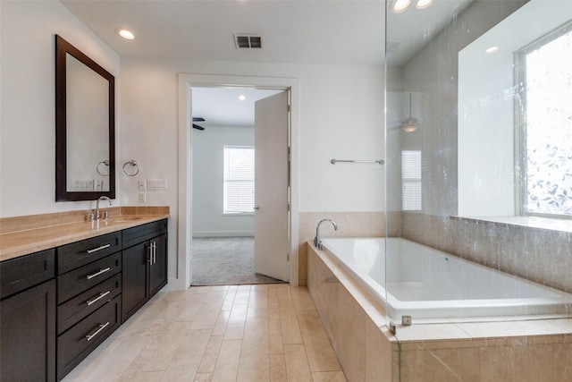 bathroom featuring vanity, tiled bath, and ceiling fan