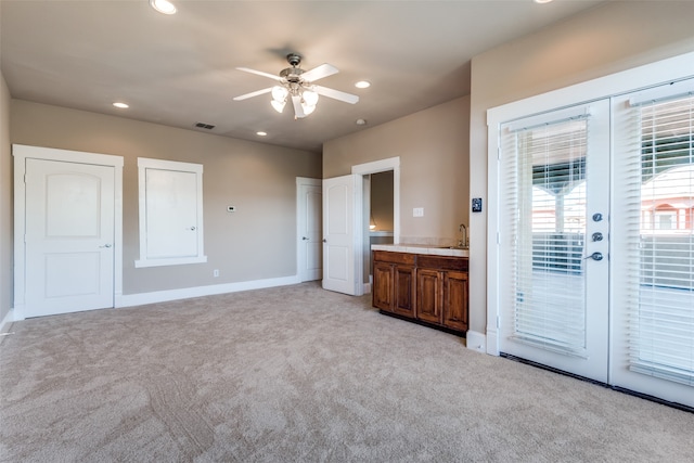 unfurnished bedroom with access to outside, ensuite bathroom, sink, ceiling fan, and light colored carpet