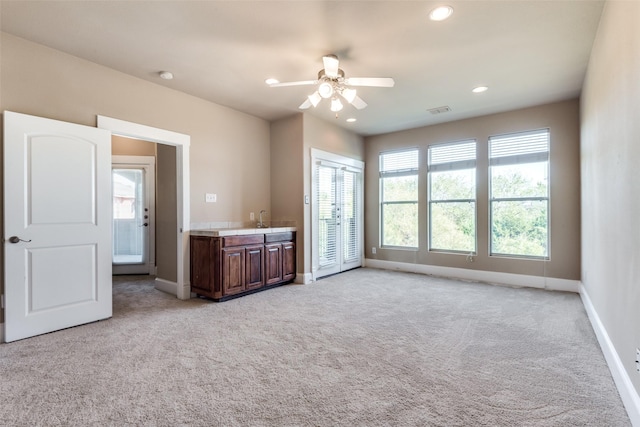 interior space featuring ceiling fan, light colored carpet, and sink