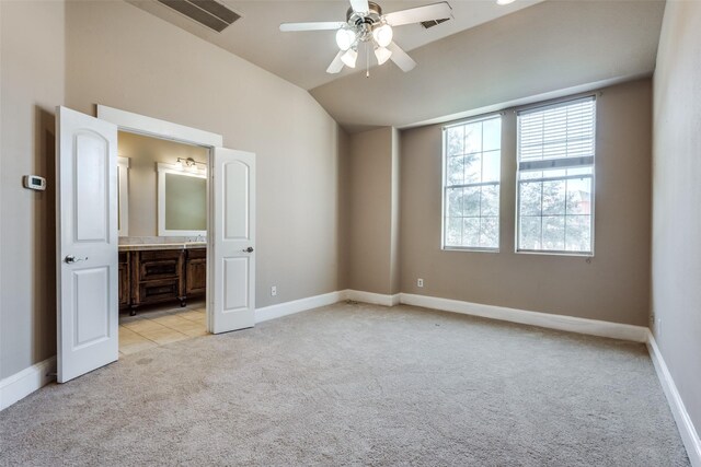 unfurnished bedroom featuring ceiling fan, light colored carpet, ensuite bathroom, and vaulted ceiling