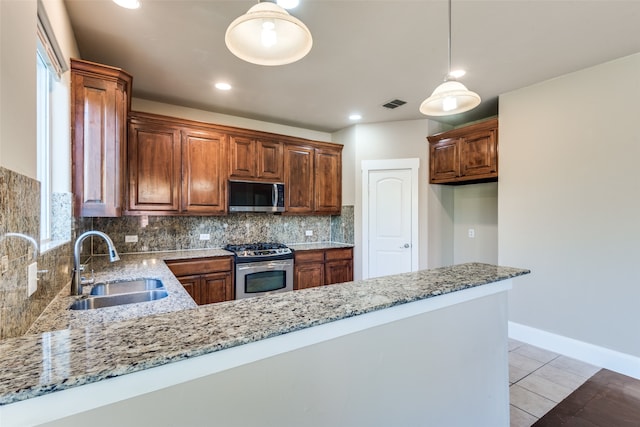 kitchen featuring kitchen peninsula, light stone countertops, sink, and appliances with stainless steel finishes