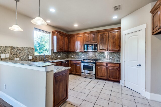 kitchen featuring sink, hanging light fixtures, stainless steel appliances, tasteful backsplash, and light stone counters