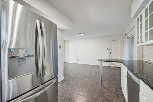 kitchen with white cabinets, stainless steel appliances, and dark stone counters