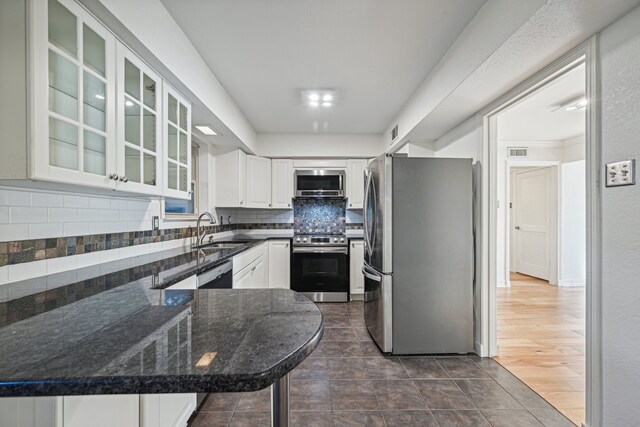 kitchen with sink, dark wood-type flooring, stainless steel appliances, backsplash, and white cabinets