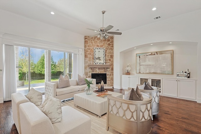 living room with hardwood / wood-style flooring, ceiling fan, a stone fireplace, and ornamental molding