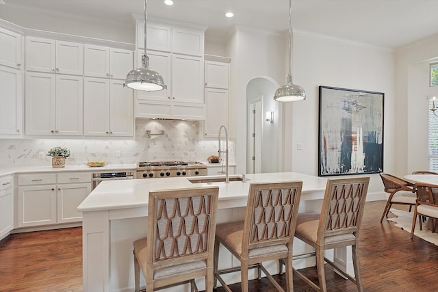 kitchen with sink, decorative light fixtures, a breakfast bar area, a center island with sink, and white cabinets