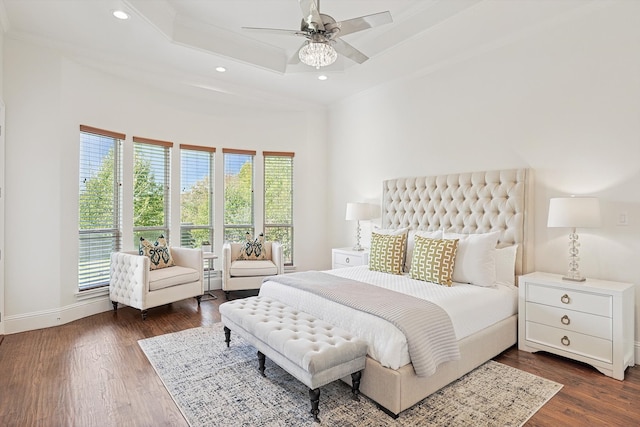 bedroom featuring ornamental molding, a tray ceiling, ceiling fan, and dark wood-type flooring