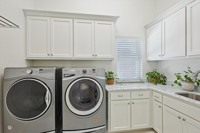 washroom with cabinets, washer and dryer, and sink