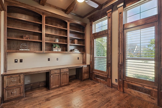 unfurnished office featuring beam ceiling, ceiling fan, dark hardwood / wood-style floors, crown molding, and built in desk