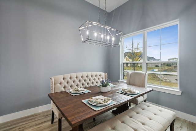 dining room with a high ceiling, hardwood / wood-style flooring, a wealth of natural light, and a notable chandelier