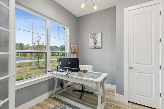 office with a chandelier, light hardwood / wood-style floors, and a healthy amount of sunlight