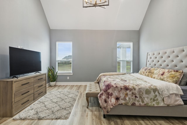 bedroom featuring a chandelier, light hardwood / wood-style floors, lofted ceiling, and multiple windows