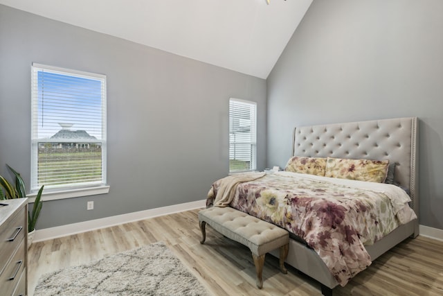 bedroom featuring multiple windows, light hardwood / wood-style flooring, and vaulted ceiling