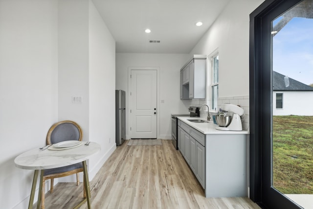 kitchen featuring gray cabinets, light wood-type flooring, sink, and appliances with stainless steel finishes