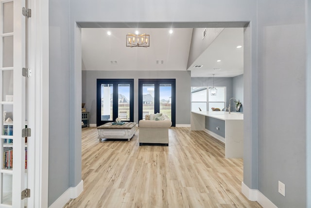 interior space featuring a chandelier, french doors, light hardwood / wood-style floors, and vaulted ceiling