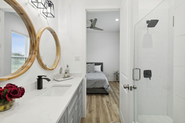 bathroom with ceiling fan, a shower with door, vanity, and hardwood / wood-style flooring