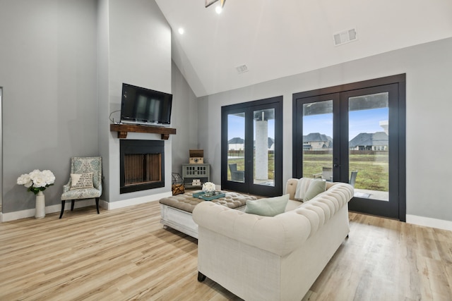 living room featuring french doors, light hardwood / wood-style floors, and high vaulted ceiling