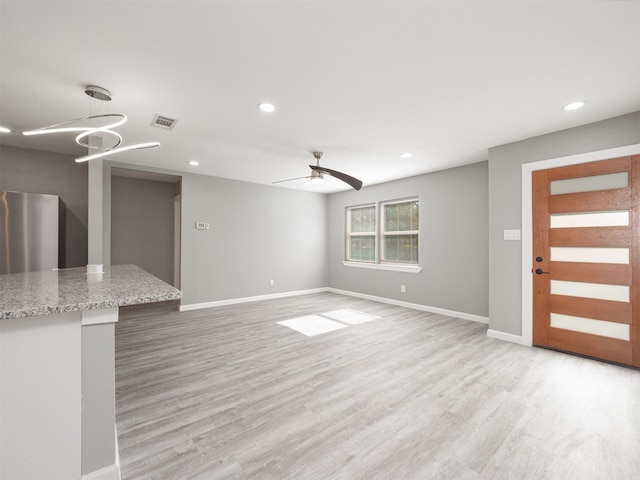 unfurnished living room featuring ceiling fan and light hardwood / wood-style floors