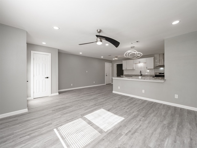 unfurnished living room featuring ceiling fan and light wood-type flooring