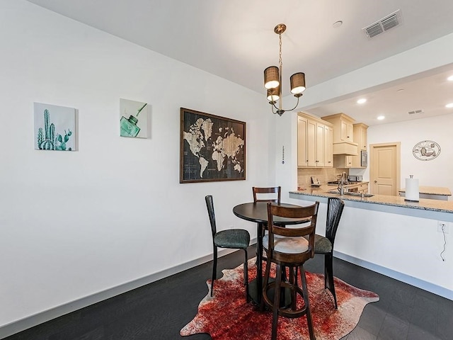 dining space with sink, dark wood-type flooring, and a notable chandelier