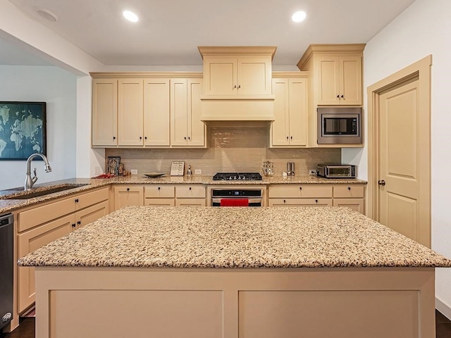 kitchen with cream cabinets, sink, decorative backsplash, light stone counters, and stainless steel appliances