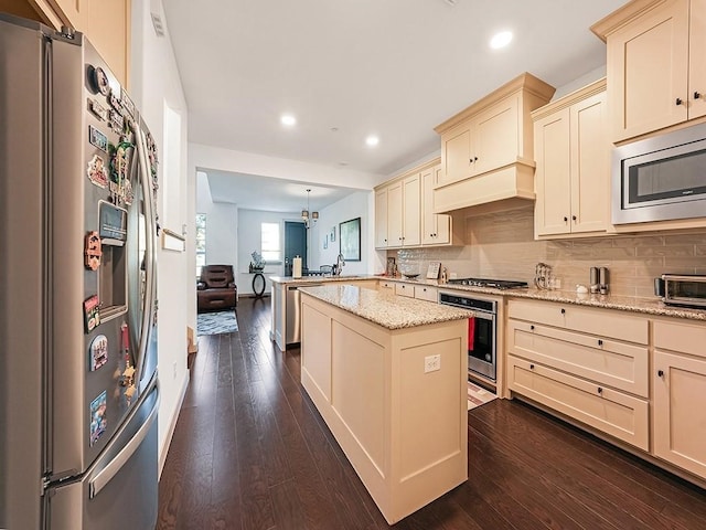 kitchen featuring pendant lighting, a center island, light stone countertops, dark hardwood / wood-style flooring, and stainless steel appliances